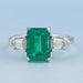 front view of emerald gemstone and bullet-cut diamond three-stone engagement ring