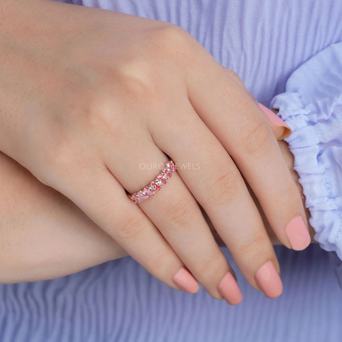 pink oval-cut seven stone lab diamond wedding band on model's finger