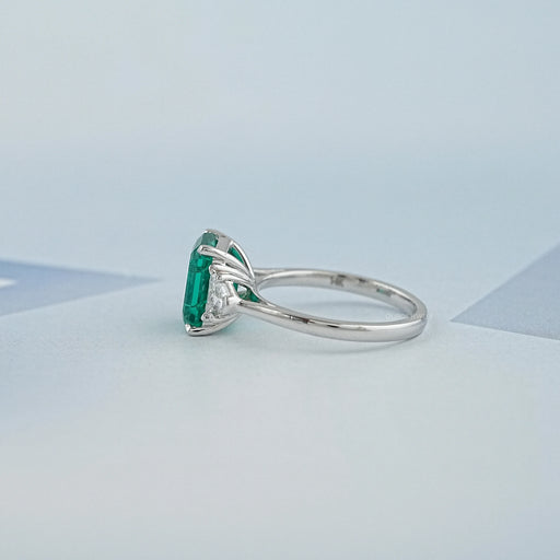side view of green emerald gemstone with shield cut diamond 3 stone engagement ring