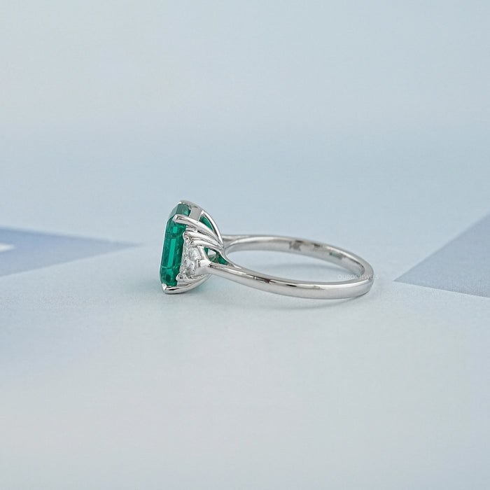 side view of green emerald gemstone with shield cut diamond 3 stone engagement ring