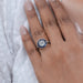 OEC round diamond surround with sapphire baguette halo wedding ring in finger