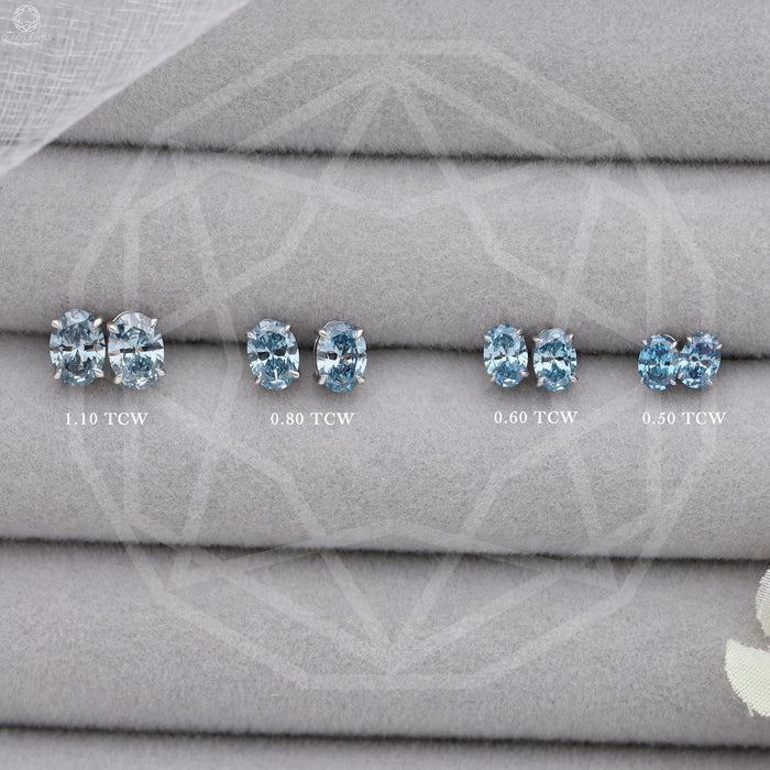 Blue Oval Cut Lab Diamond Stud Earrings in various sizes: 1.10 TCW, 0.80 TCW, 0.60 TCW, and 0.50 TCW, arranged on a gray fabric display.
