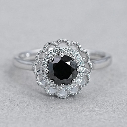 top view of round black diamond double halo engagement ring on grey fabric