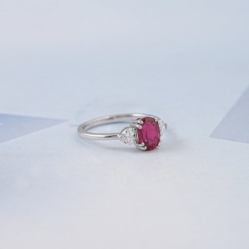 side view of oval red ruby gemstone & heart diamond three stone engagement ring