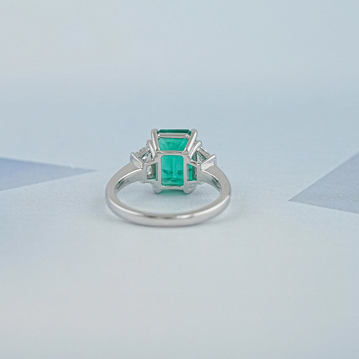 back view of green emerald gemstone with trapezoid diamond 3 stone engagement ring