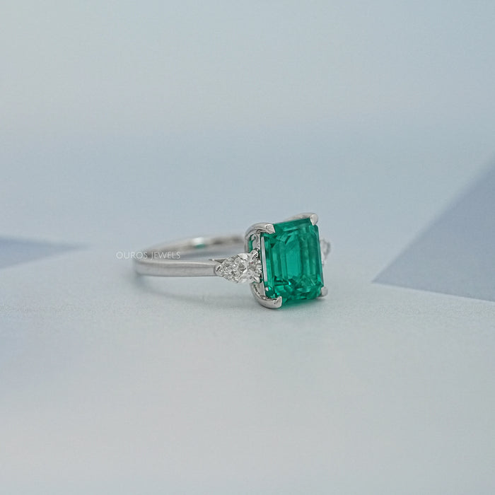 side view of green emerald gemstone pear diamond three stone engagement ring