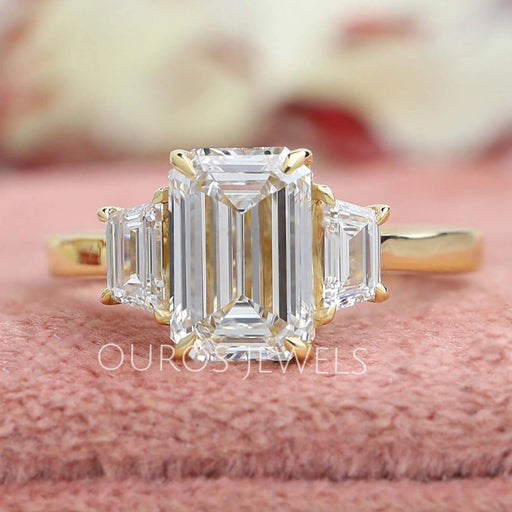 front view of emerald cut diamond three stone engagement ring in yellow gold band