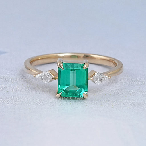 front view of green emerald gemstone and kite cut three stone engagement ring