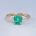 front view of green emerald gemstone and kite cut three stone engagement ring
