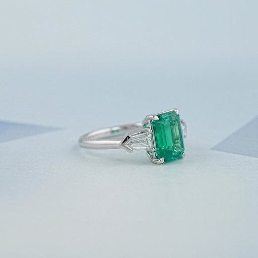 right view of emerald gemstone and bullet-cut diamond three-stone engagement ring