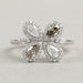 top view of olive pear cut lab diamond floral halo engagement ring on grey fabric