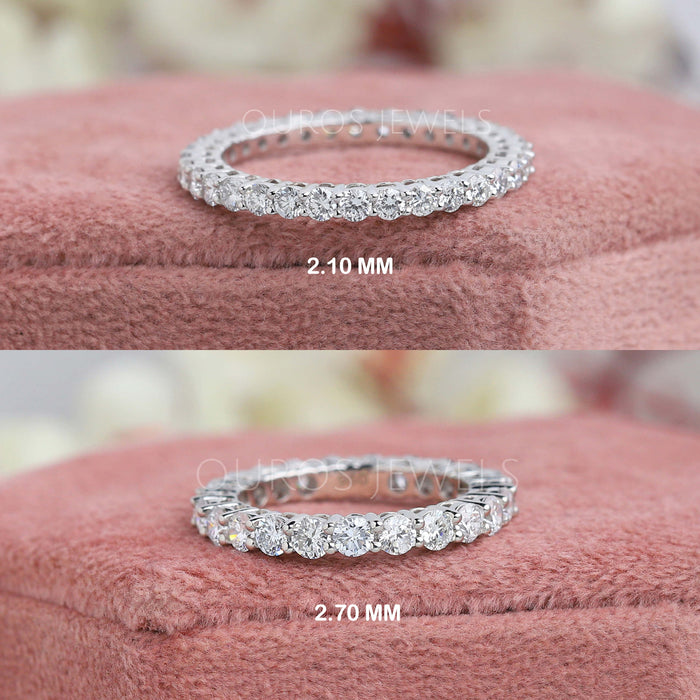 The two close-up images of Round Cut Lab Diamond Eternity Wedding Band. The first band has diamonds measuring 2.10 MM, and the second band has diamonds measuring 2.70 MM, both placed on a soft pink fabric background.