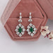 green gemstone halo earrings in white gold
