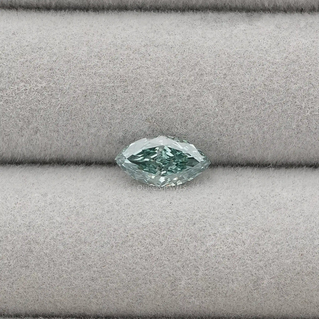 1.23 Carat Green Marquise Cut Loose Diamond placed on a light gray fabric background, showcasing its unique shape and green hue.