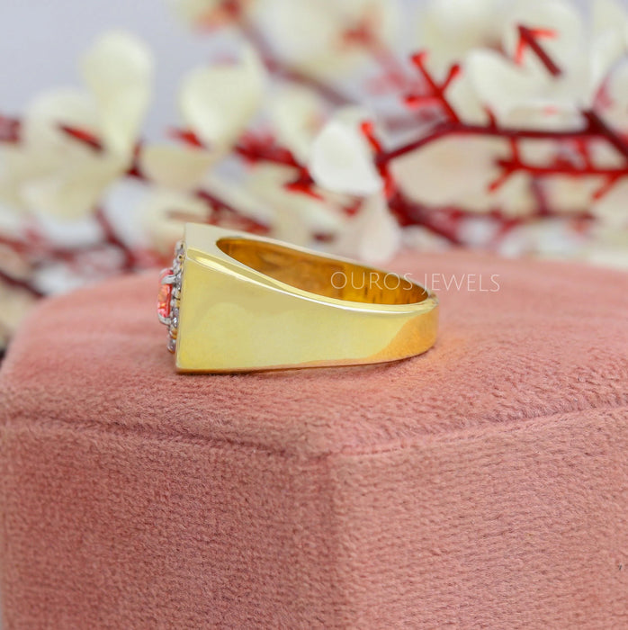 side view of pink round cut diamond halo yellow gold men's wedding band on jewelry box