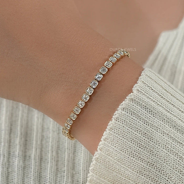 asscher cut ethically sourced diamonds bezel set tennis bracelet in yellow gold on hand