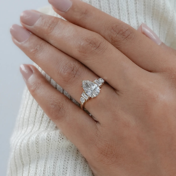 pear and baguette cut lab diamond five stone engagement ring on model's finger