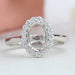 front view of oval-shaped halo semi-mount engagement ring on grey fabric