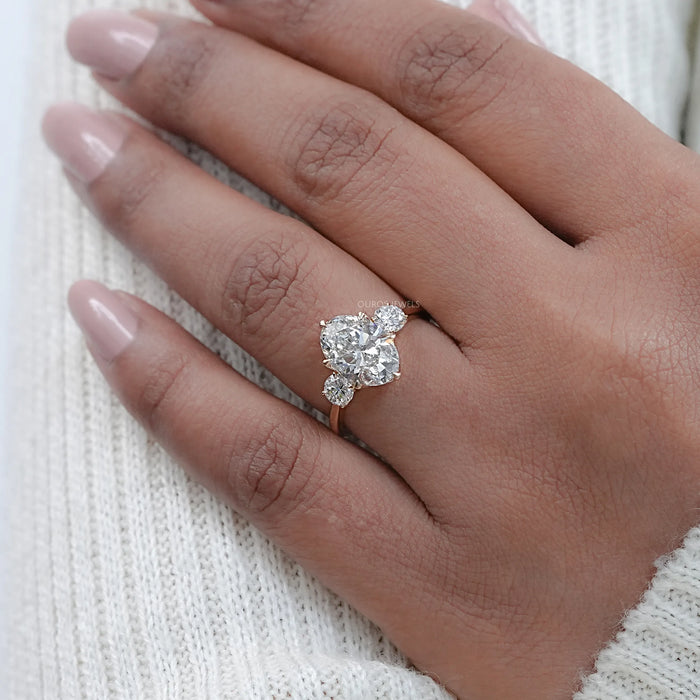 oval cut lab made diamond three stone engagement ring on model's finger