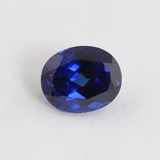 front view of blue sapphire oval cut lab grown gemstone on fabric