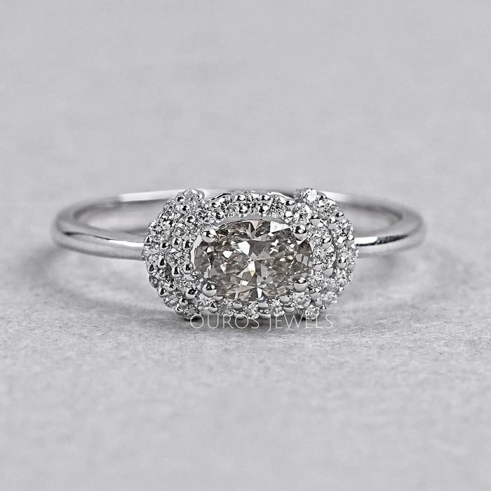 oval diamond halo engagement ring with olive center stone view on grey background