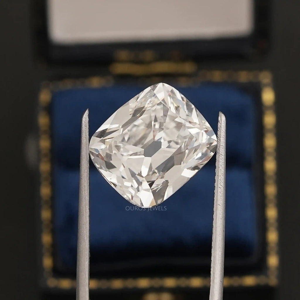 10 Carat IGI Certified Old Mine Cushion Cut Diamond held by tweezers with a blue and gold background.
