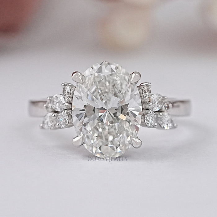 front view of oval-cut lab diamond cluster solitaire engagement ring on grey fabric