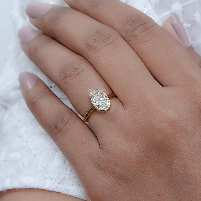 oval diamond hidden halo bezel set engagement ring worn on finger view