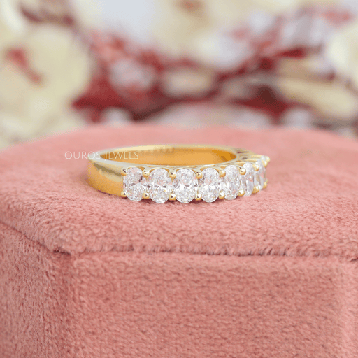 side view of oval cut diamond shared prong half eternity band yellow gold