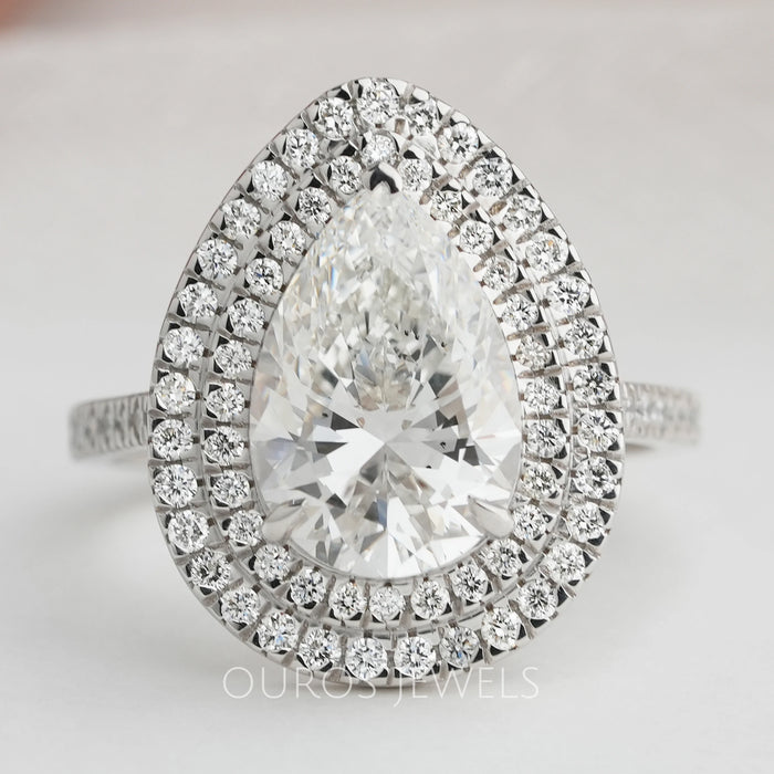 pear cut lab diamond double halo engagement ring's front view on grey fabric
