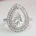 pear cut lab diamond double halo engagement ring's front view on grey fabric