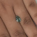 1.62 Carat Fancy Vivid Green Pear Cut Lab Grown Diamond placed on a person's finger for scale, showing the diamond's size and color against the skin.