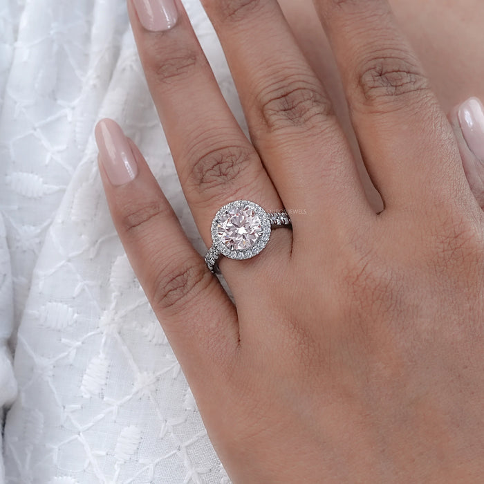 pink round-cut lab diamond solitaire halo engagement ring on model's finger