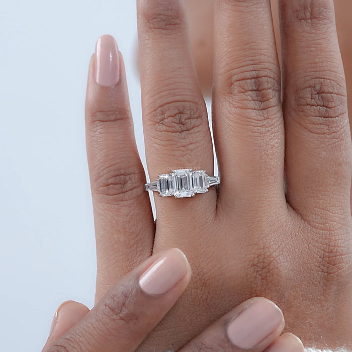 emerald cut diamond five stone engagement ring with white gold band in finger