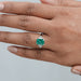 green emerald gemstone with shield cut diamond 3 stone engagement ring in finger