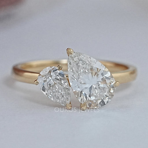 front view of two pear-cut lab diamond toi et moi engagement ring on grey fabric