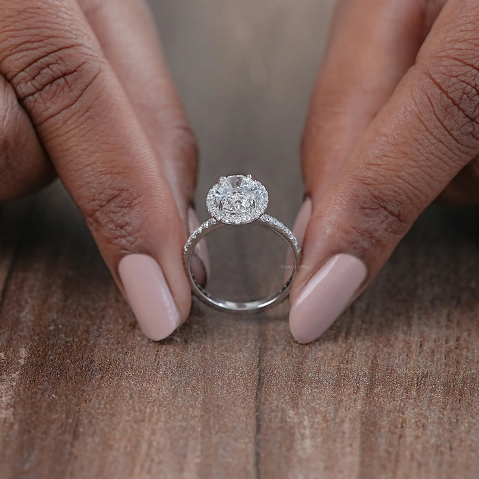 close view of oval cut lab diamond halo engagement ring on brown background
