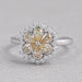 front view of yellow pear diamond floral halo engagement ring on grey fabric