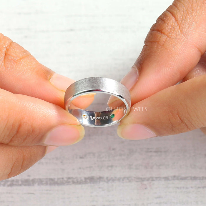 round cut gemstone inside men's diamond ring white gold shown between finger