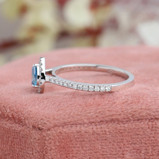 side view of blue pear-cut lab diamond halo colored engagement ring on jewelry box