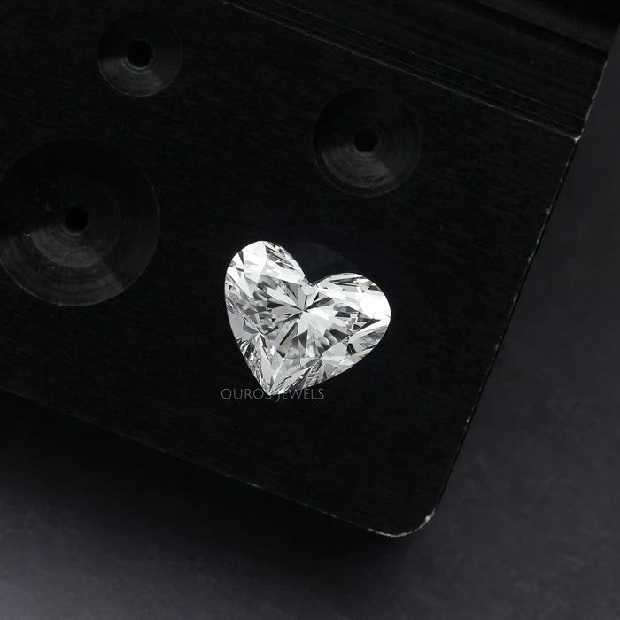 1 Carat IGI Certified Heart Cut Lab Grown Diamond placed on a black surface, showcasing its intricate facets and brilliant sparkle.
