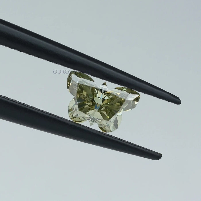 green butterfly shape diamond holded with tweezer