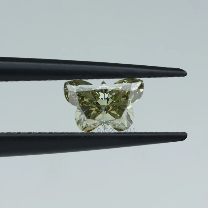 green colored butterfly shape lab diamond holded with black tweezer